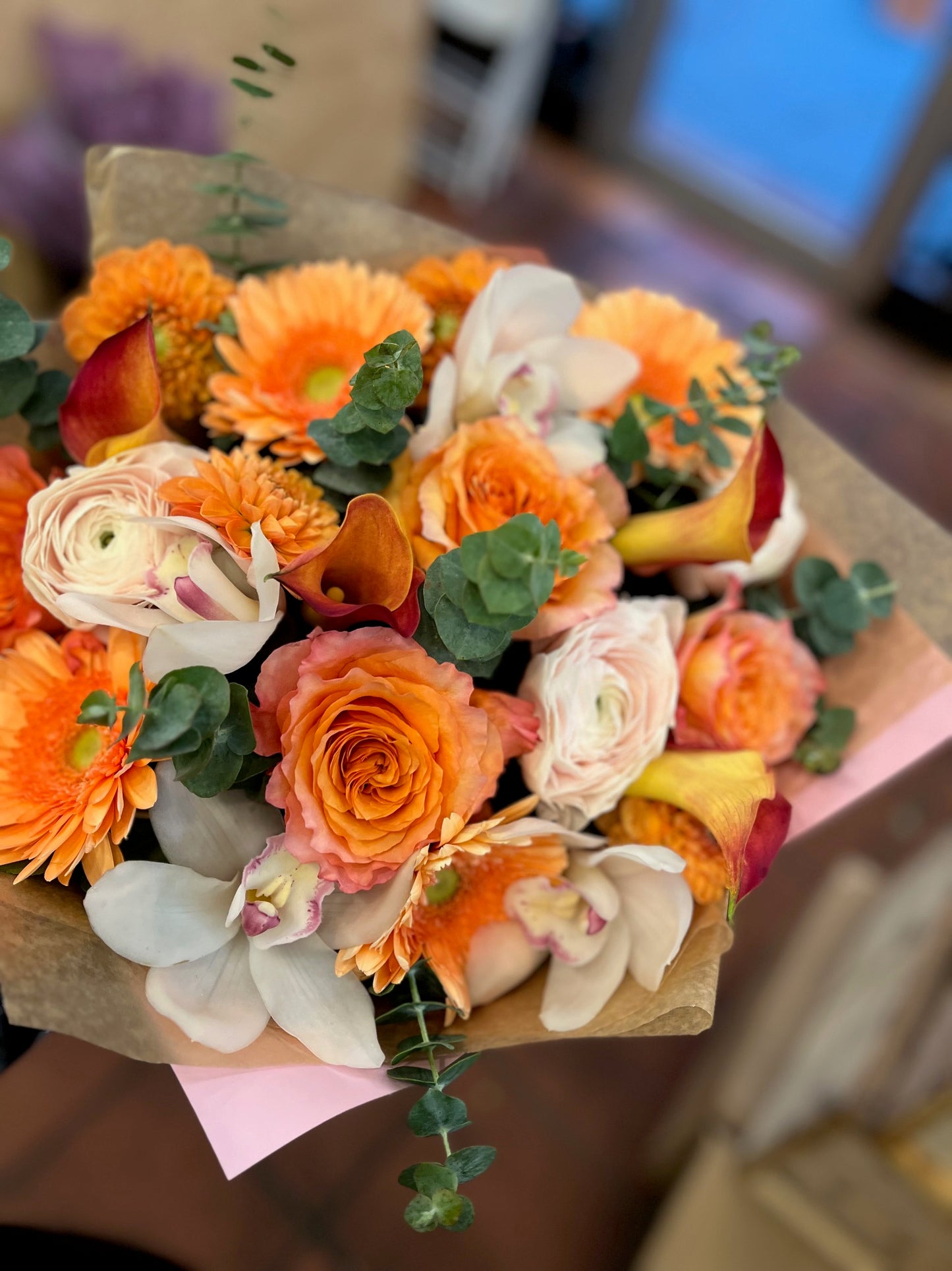 Orange pink roses, gerbera daisy, dahlias, cymbidium orchid heads, eucalyptus and ranunculus sunrise bouquet – Jerome Florists NYC
