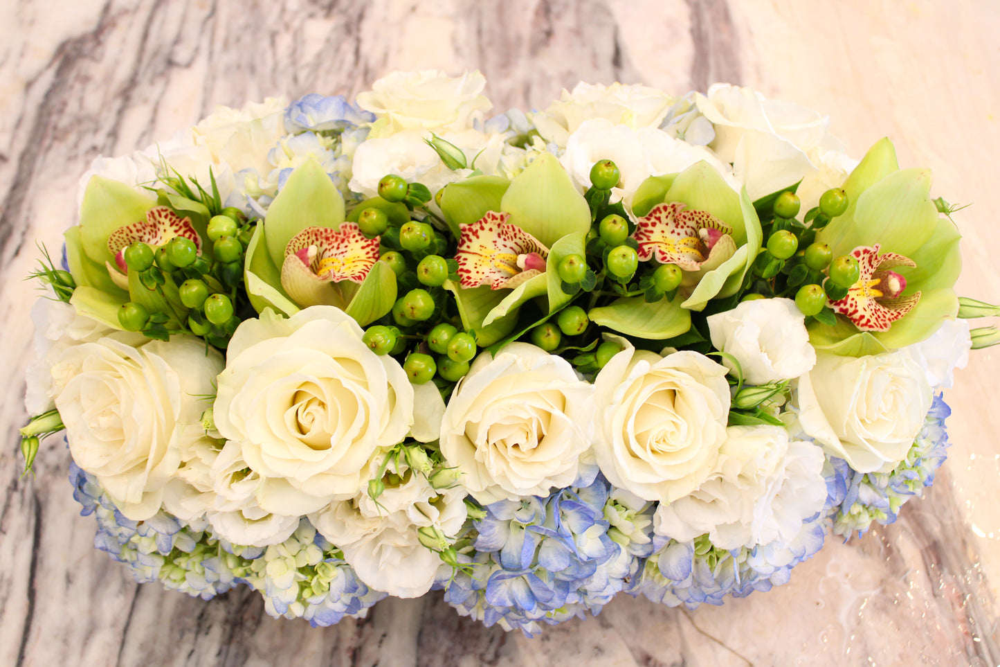 Blue hydrangea, green cymbidium orchids and hypericum berries, and white rose centerpiece – Jerome Florists NYC