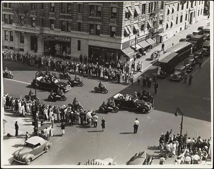 Vintage street scene with cars, motorcycles, and people on a city street. Photo of Jerome Florists from 1930s or 1940s