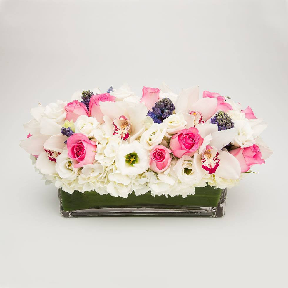 White hydrangea, pink roses, blue hyacinth, lisianthus and cymbidium orchid pastel centerpiece – Jerome Florists NYC